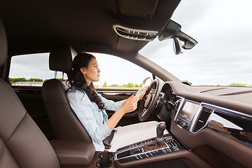 Image showing happy woman driving car with smarhphone
