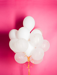 Image showing close up of white helium balloons over pink