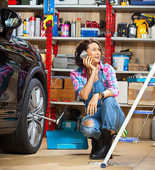 Image showing pretty woman mechanic talking on mobile with client