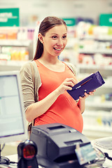 Image showing pregnant woman with wallet at cashbox in drugstore