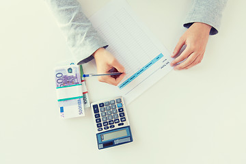 Image showing close up of hands counting money with calculator