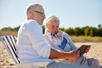 Image showing happy senior couple with tablet pc on summer beach