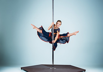 Image showing The strong and graceful young girl performing acrobatic exercises on pylon