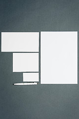 Image showing Mock-up business template with cards, papers, pen. Gray background.