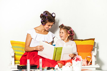 Image showing Little girl sitting with her mother and looking at a photo album