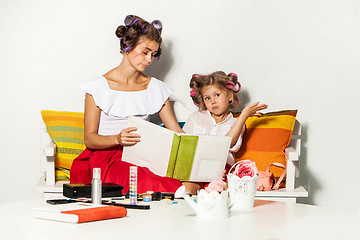 Image showing Little girl sitting with her mother and looking at a photo album