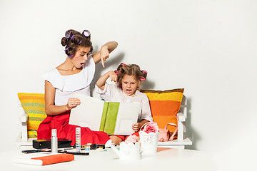 Image showing Little girl sitting with her mother and looking at a photo album