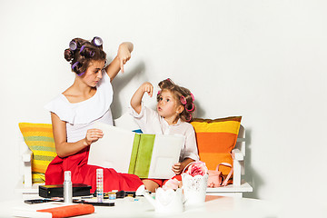 Image showing Little girl sitting with her mother and looking at a photo album