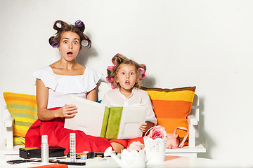 Image showing Little girl sitting with her mother and looking at a photo album