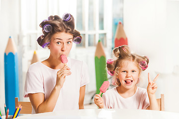 Image showing Little girl sitting with her mother and eating ice cream