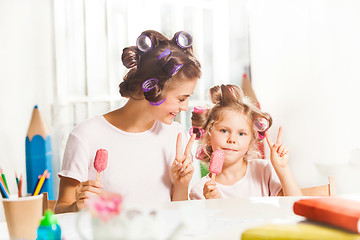 Image showing Little girl sitting with her mother and eating ice cream