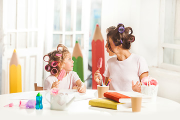 Image showing Little girl sitting with her mother and eating ice cream