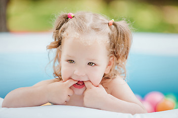 Image showing The little baby girl playing with toys in inflatable pool in the summer sunny day