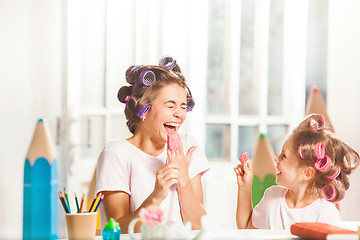 Image showing Little girl sitting with her mother and eating ice cream