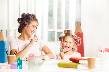 Image showing Little girl sitting with her mother and eating ice cream