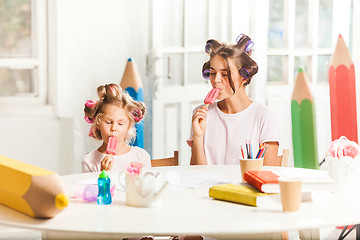 Image showing Little girl sitting with her mother and eating ice cream