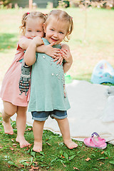 Image showing The two little baby girls playing against green grass