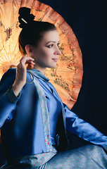 Image showing Young Woman Sitting With a Chinese Umbrella