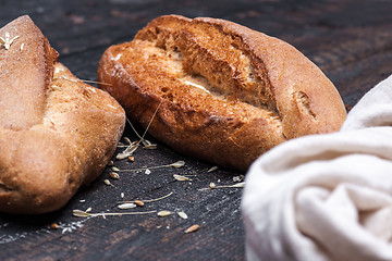 Image showing Rustic bread on wood table. Dark moody background with free text space.