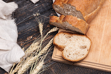 Image showing Rustic bread on wood table. Dark wooden background