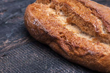 Image showing Rustic bread on wood table. Dark moody background with free text space.