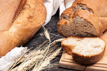 Image showing Rustic bread on wood table. Dark wooden background