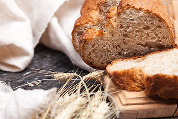 Image showing Rustic bread on wood table. Dark wooden background