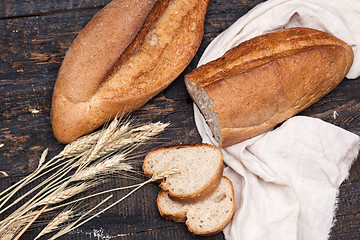 Image showing Rustic bread on wood table. Dark wooden background