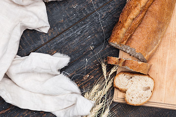 Image showing Rustic bread on wood table. Dark woody background with free text space.
