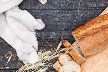 Image showing Rustic bread on wood table. Dark woody background with free text space.