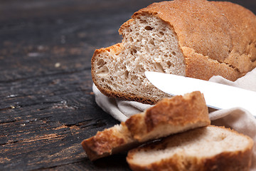 Image showing Rustic bread on wood table. Dark woody background with free text space.