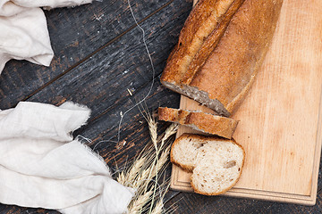 Image showing Rustic bread on wood table. Dark woody background with free text space.