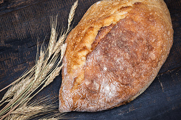 Image showing Rustic bread on wood table. Dark moody background with free text space.