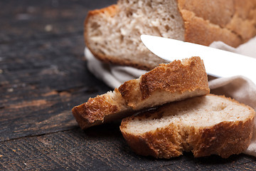 Image showing Rustic bread on wood table. Dark woody background with free text space.