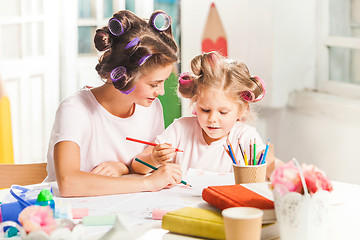 Image showing The young mother and her little daughter drawing with pencils at home