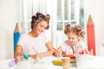 Image showing The young mother and her little daughter drawing with pencils at home