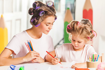 Image showing The young mother and her little daughter drawing with pencils at home