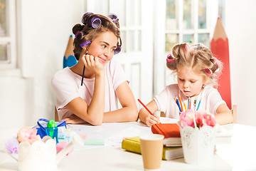 Image showing The young mother and her little daughter drawing with pencils at home