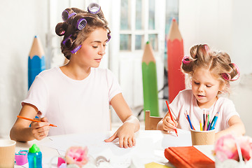 Image showing The young mother and her little daughter drawing with pencils at home