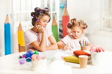 Image showing The young mother and her little daughter drawing with pencils at home