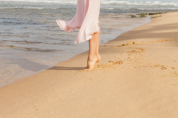 Image showing Woman legs walking on the beach sand