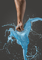 Image showing Close-up of a man\'s fist punching through liquid