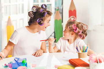 Image showing The young mother and her little daughter drawing with pencils at home