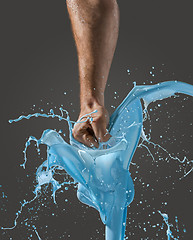 Image showing Close-up of a man\'s fist punching through liquid