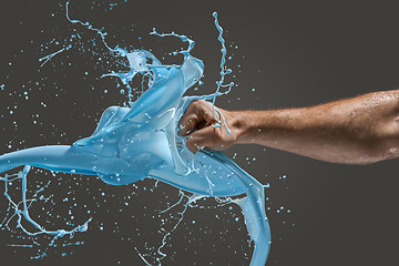 Image showing Close-up of a man\'s fist punching through liquid