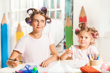 Image showing The young mother and her little daughter drawing with pencils at home