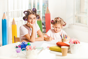 Image showing The young mother and her little daughter drawing with pencils at home