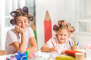 Image showing The young mother and her little daughter drawing with pencils at home