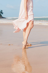 Image showing Woman legs walking on the beach sand