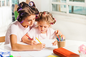 Image showing The young mother and her little daughter drawing with pencils at home